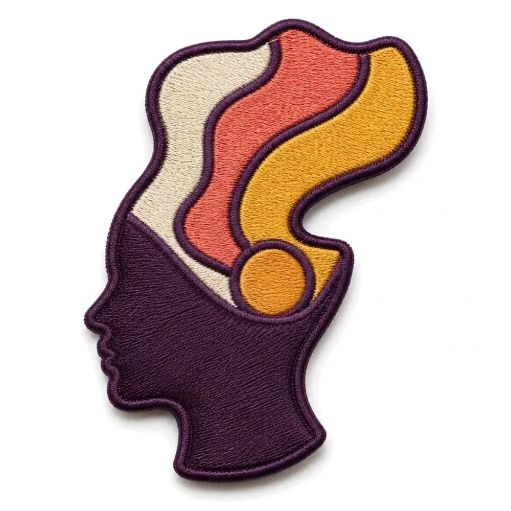 Écusson brodé découpé à la forme d'un profil, vagues de couleur s'échappant de la tête, fil prune, corail et or